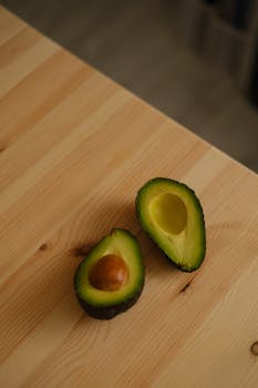 Close-up of fresh avocado halves on a wooden surface, showcasing vibrant green flesh.