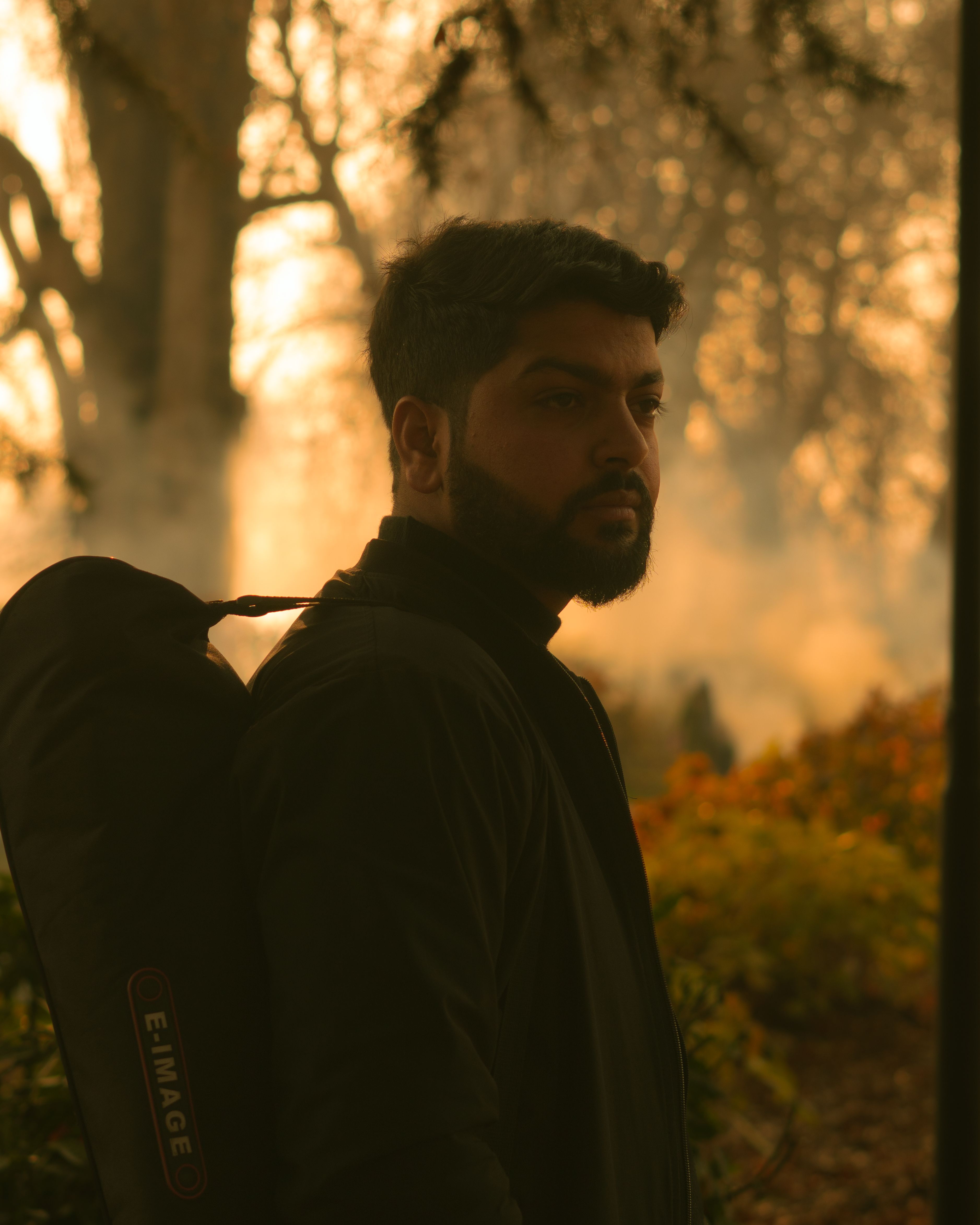 A man with a backpack hikes through a foggy forest at dawn, embracing nature's tranquility.