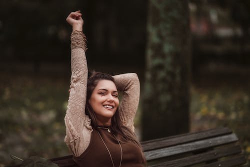 Young Woman Sitting on a Bench in a Park and Smiling 