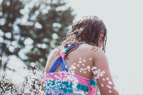 Back View of a Girl in a Swimming Costume Splashing Water 