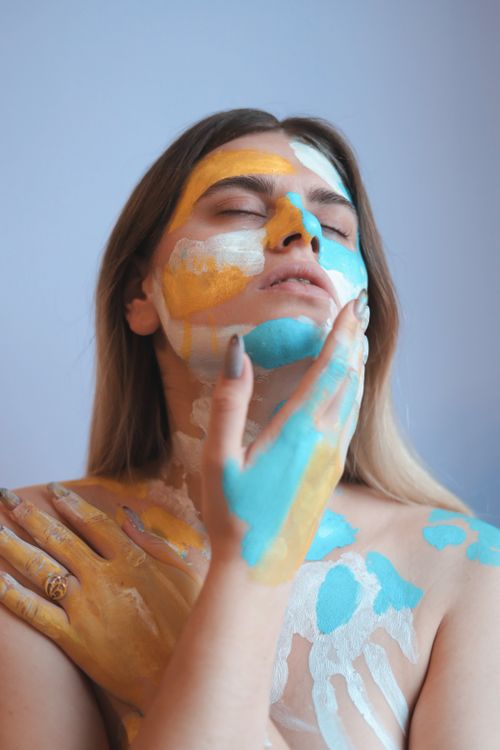 Free A serene artistic portrait of a woman with vibrant face paint expressing creativity. Stock Photo