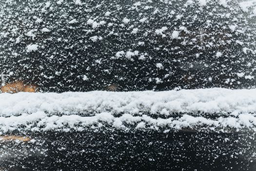 Detailed view of snow accumulating on a car window, showcasing winter weather conditions.