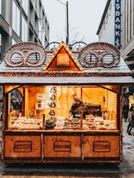 Charming winter scene of a pretzel stand selling goods in a snowy city street at dusk.