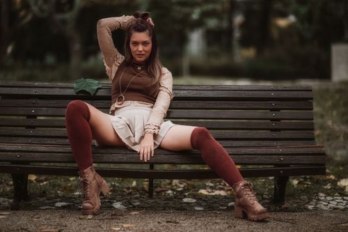 Free Fashionable woman in fall attire posing confidently on a park bench in Lisbon. Stock Photo