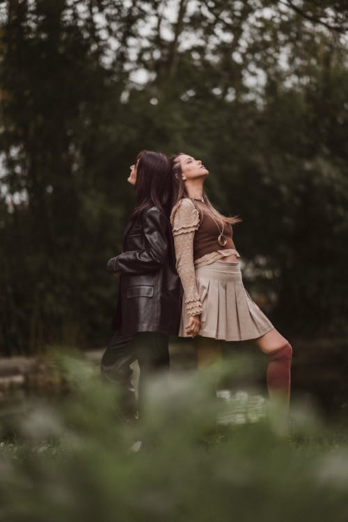 Two Women Standing Back to Back in a Park 