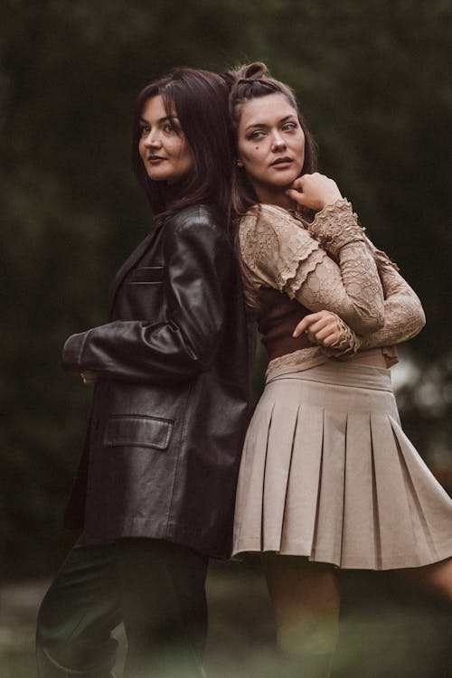 Two Fashionable Women Standing Outside Back to Back 