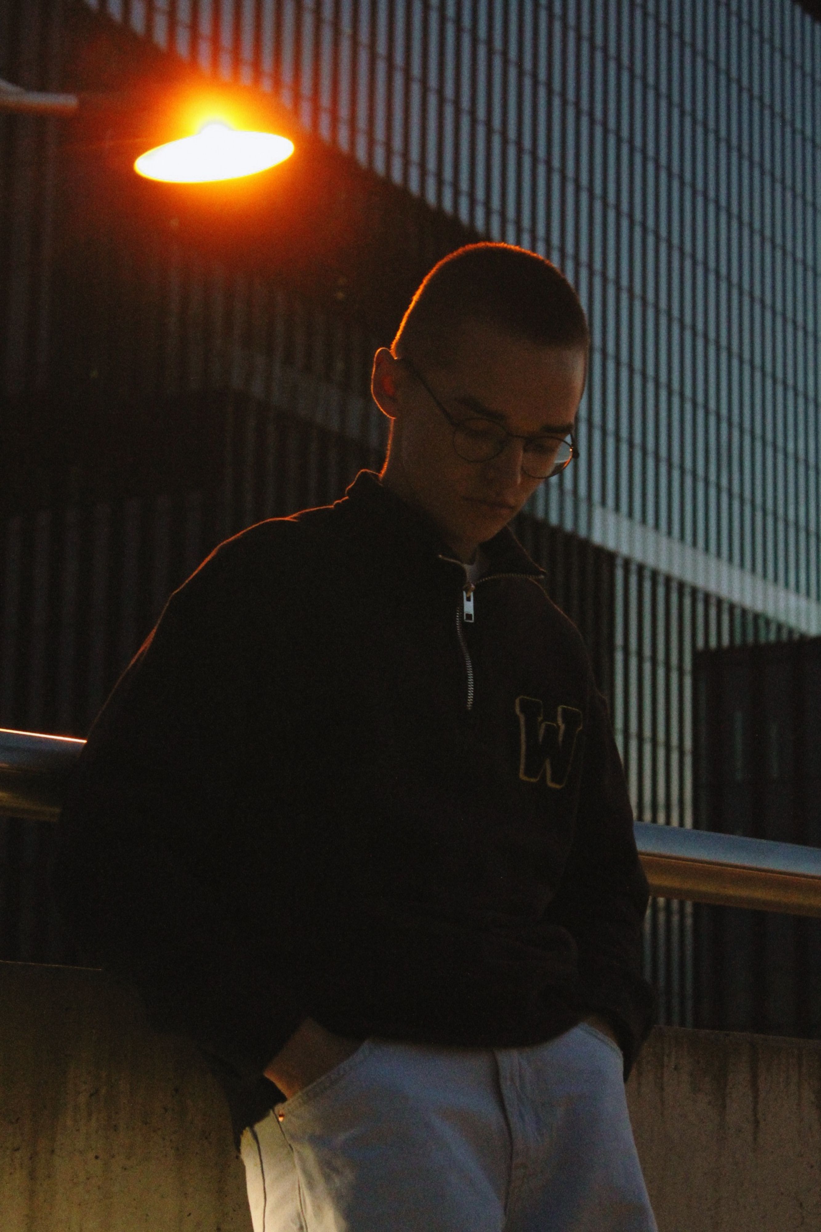 A contemplative silhouette of a man under streetlight in Katowice at night.
