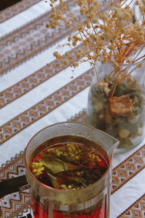 An Herbal Tea in a Pot Standing on a Table next to Dried Flowers