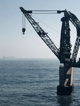 A large industrial crane extends over the serene sea in Viña del Mar, capturing Chile's maritime essence.
