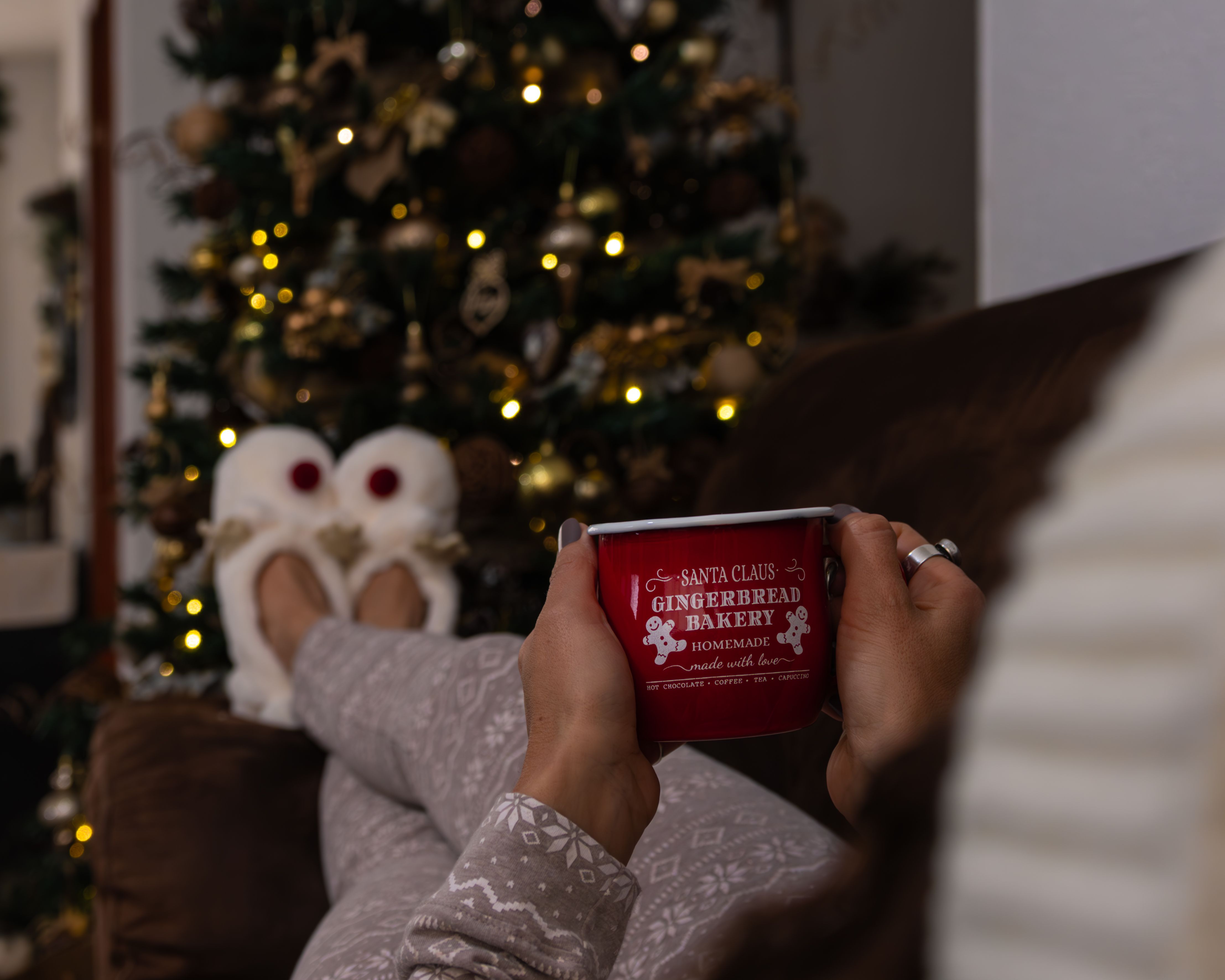 Relaxing by the Christmas tree with a hot drink in festive pajamas and slippers.