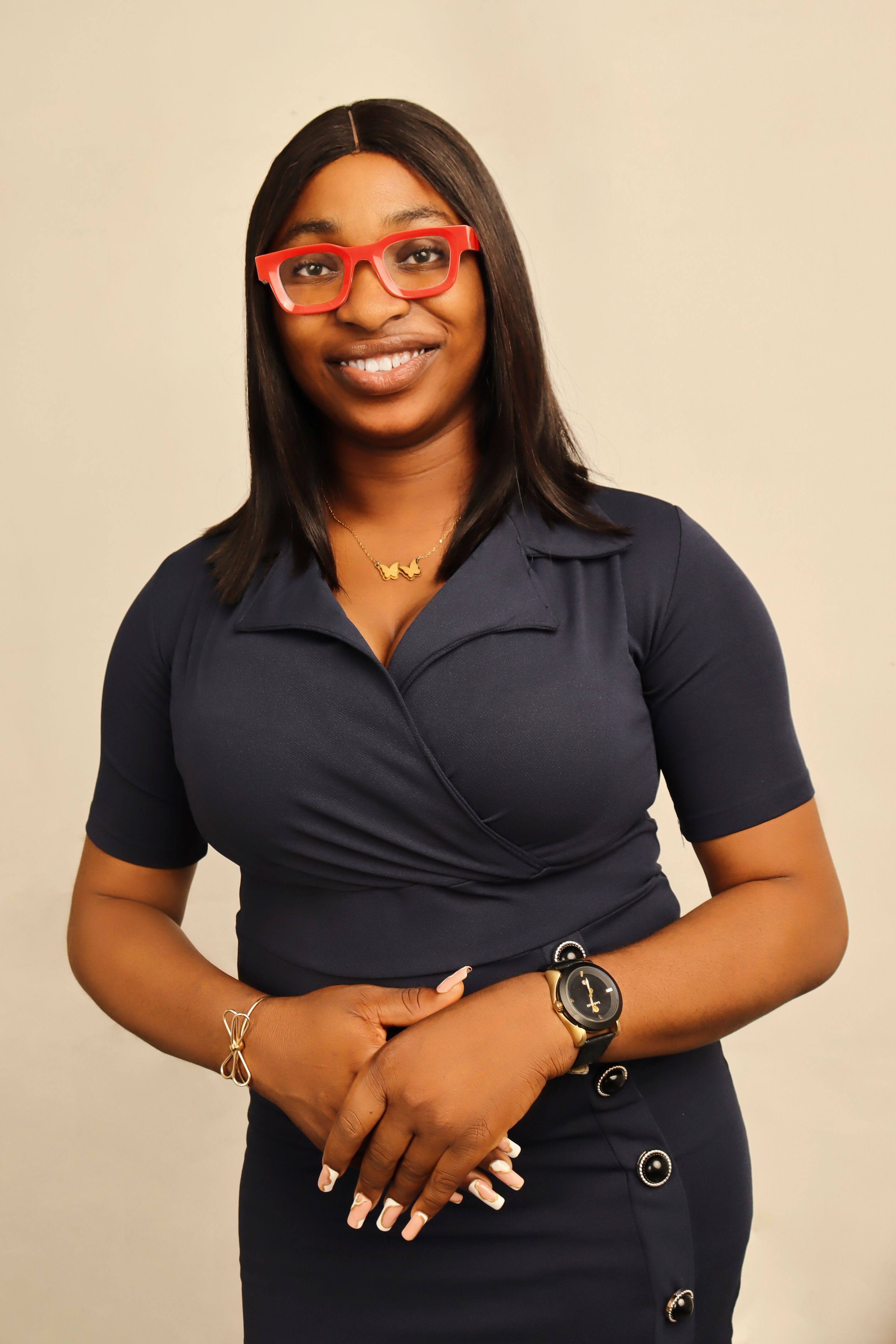 Portrait of a brunette woman in a stylish dress and red eyeglasses, smiling in a studio setting.