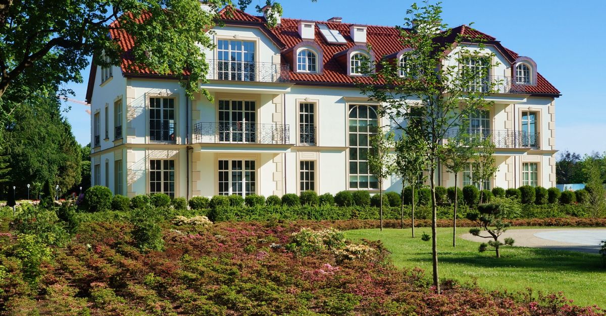 Sunlit residential building with lush garden in Gdansk Oliwa, Poland.