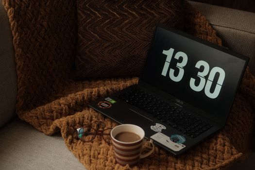 A comfortable workspace featuring a laptop and coffee cup on a cozy couch.