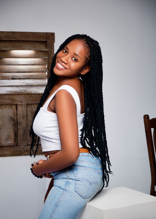 Free Portrait of a smiling woman wearing a white top and jeans indoors, capturing a happy moment. Stock Photo