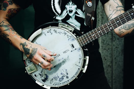 Close-up shot of a tattooed musician playing a unique banjo with custom artwork and symbols.