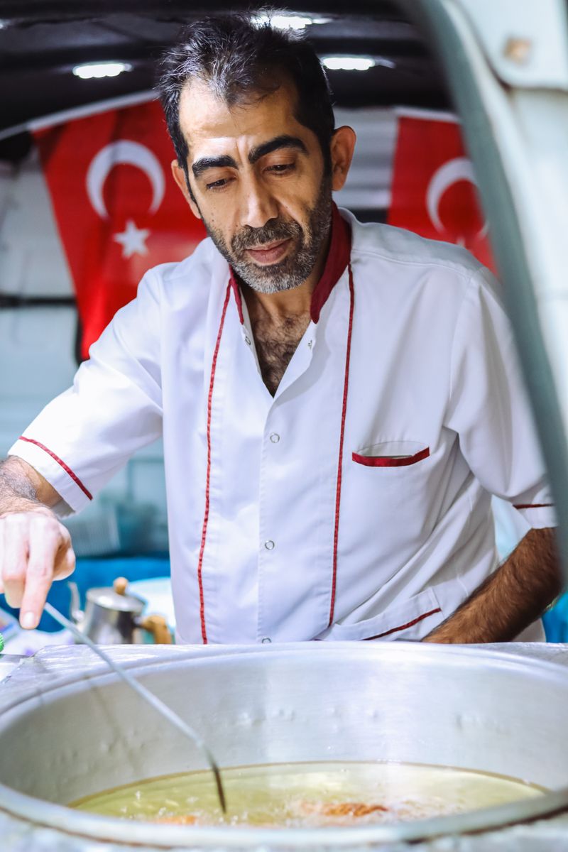 A professional chef in uniform prepares a dish in a Turkish kitchen, emphasizing traditional cooking.