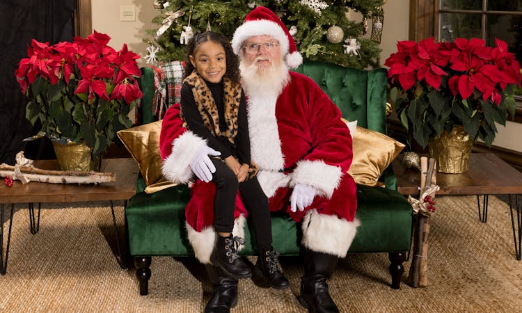 Smiling Girl Sitting On Santa Claus Lap