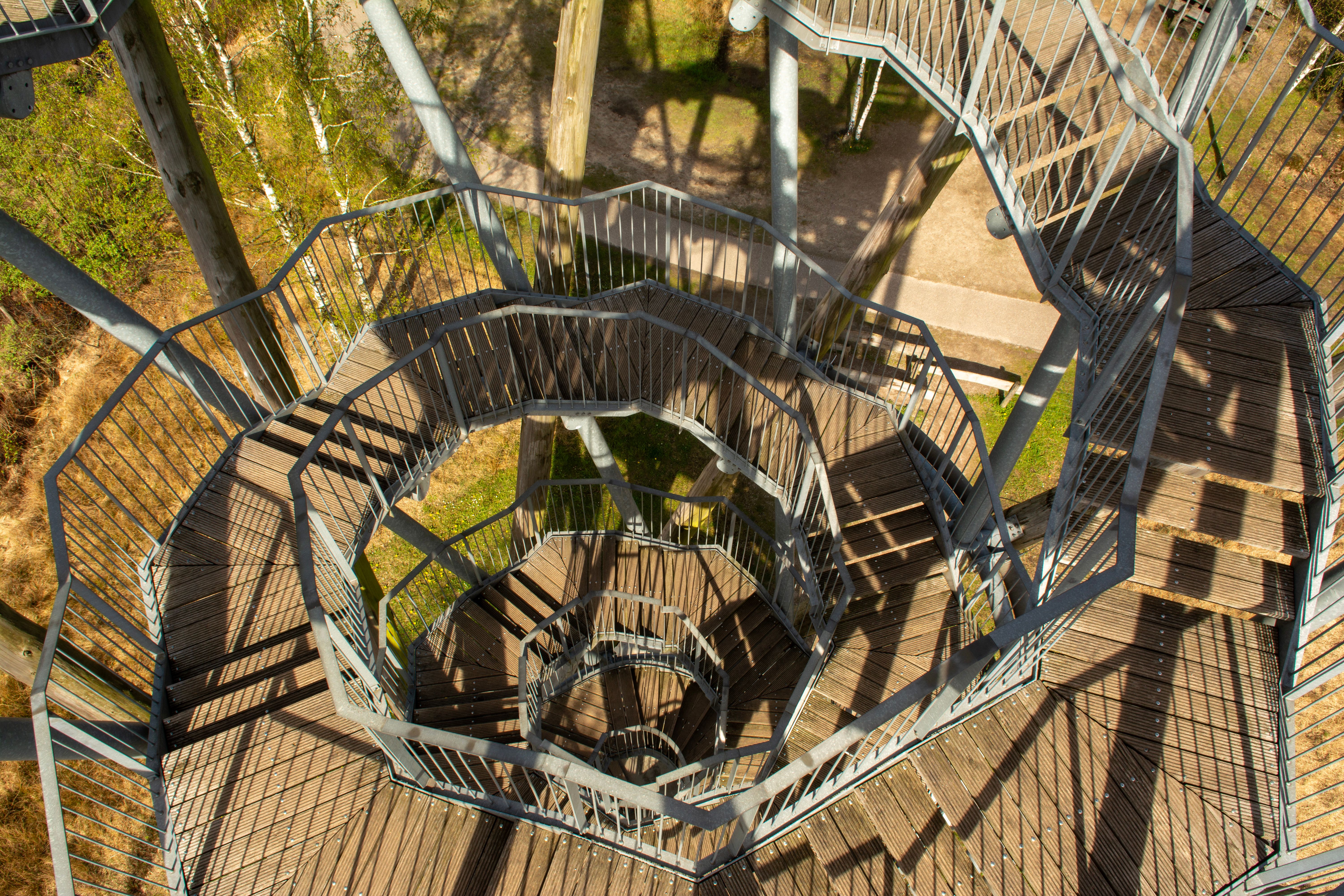 Captivating top view of a spiral metal staircase in a serene forest setting.