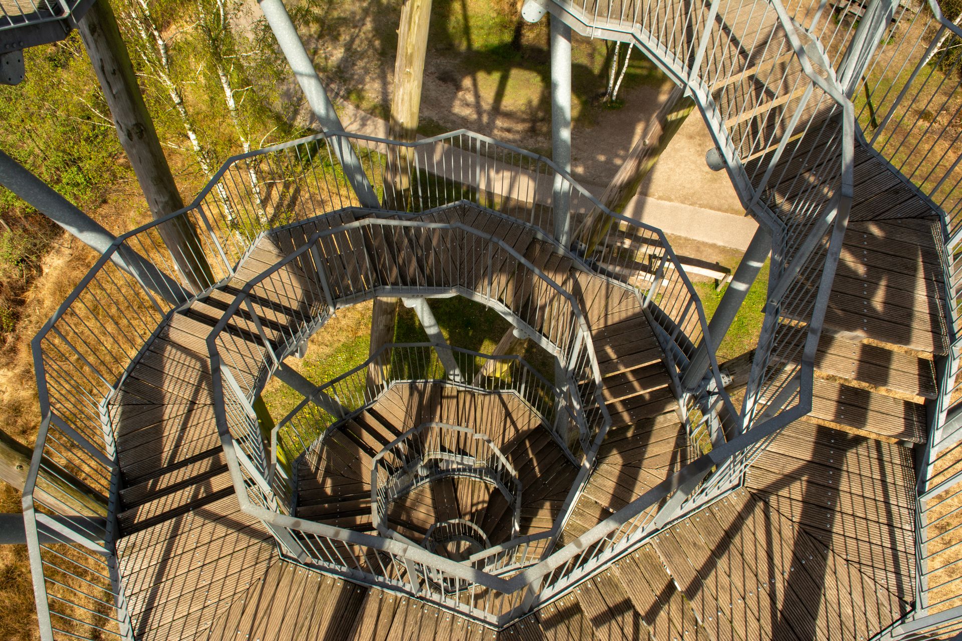 Captivating top view of a spiral metal staircase in a serene forest setting.