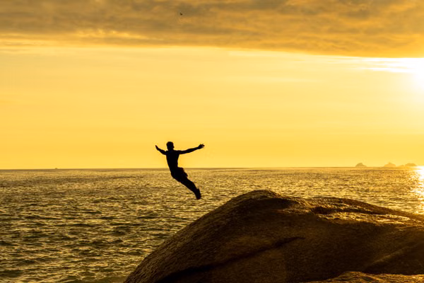 a man jumping off an ocean cliff