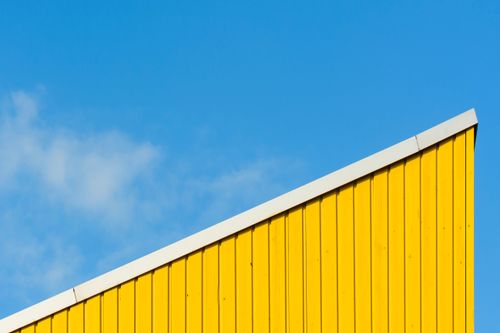 Free Minimalist architectural detail with a yellow roof against a blue sky. Stock Photo