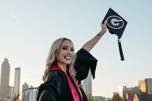 Woman in a Graduation Gown Holding up a Hat 
