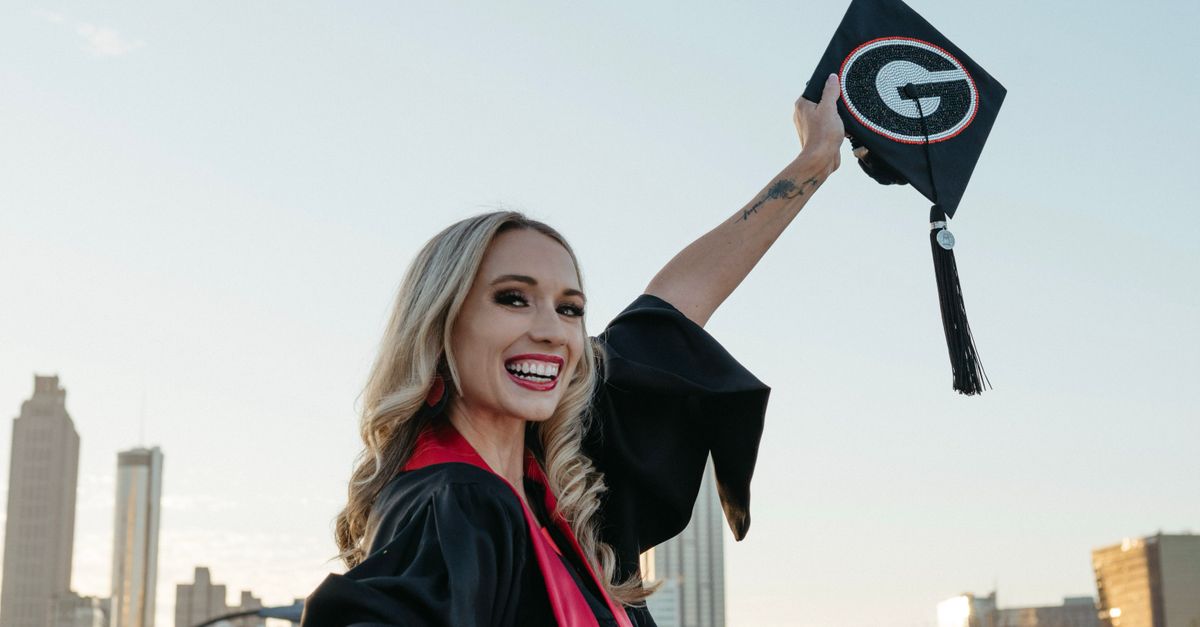 Joyful female graduate celebrating with cap in Atlanta skyline background.
