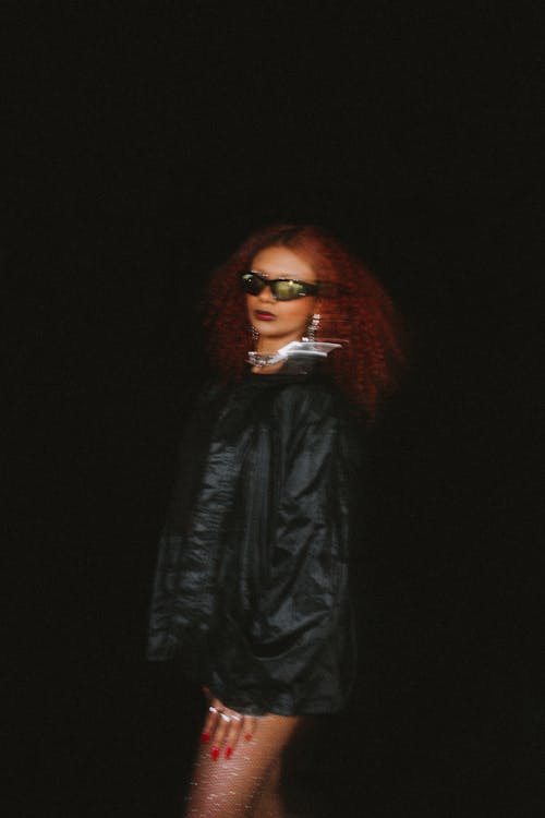 Redhead Woman Wearing a Leather Jacket, Posing against Black Background