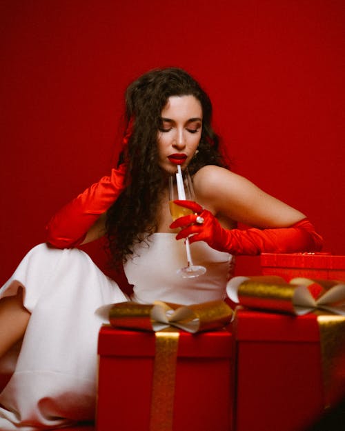 Woman Leaning on Christmas Presents Drinking Champagne 