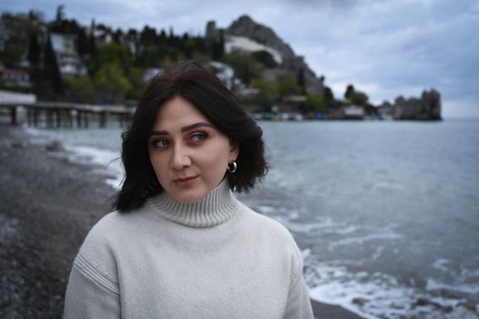 A woman in a white sweater standing on the beach