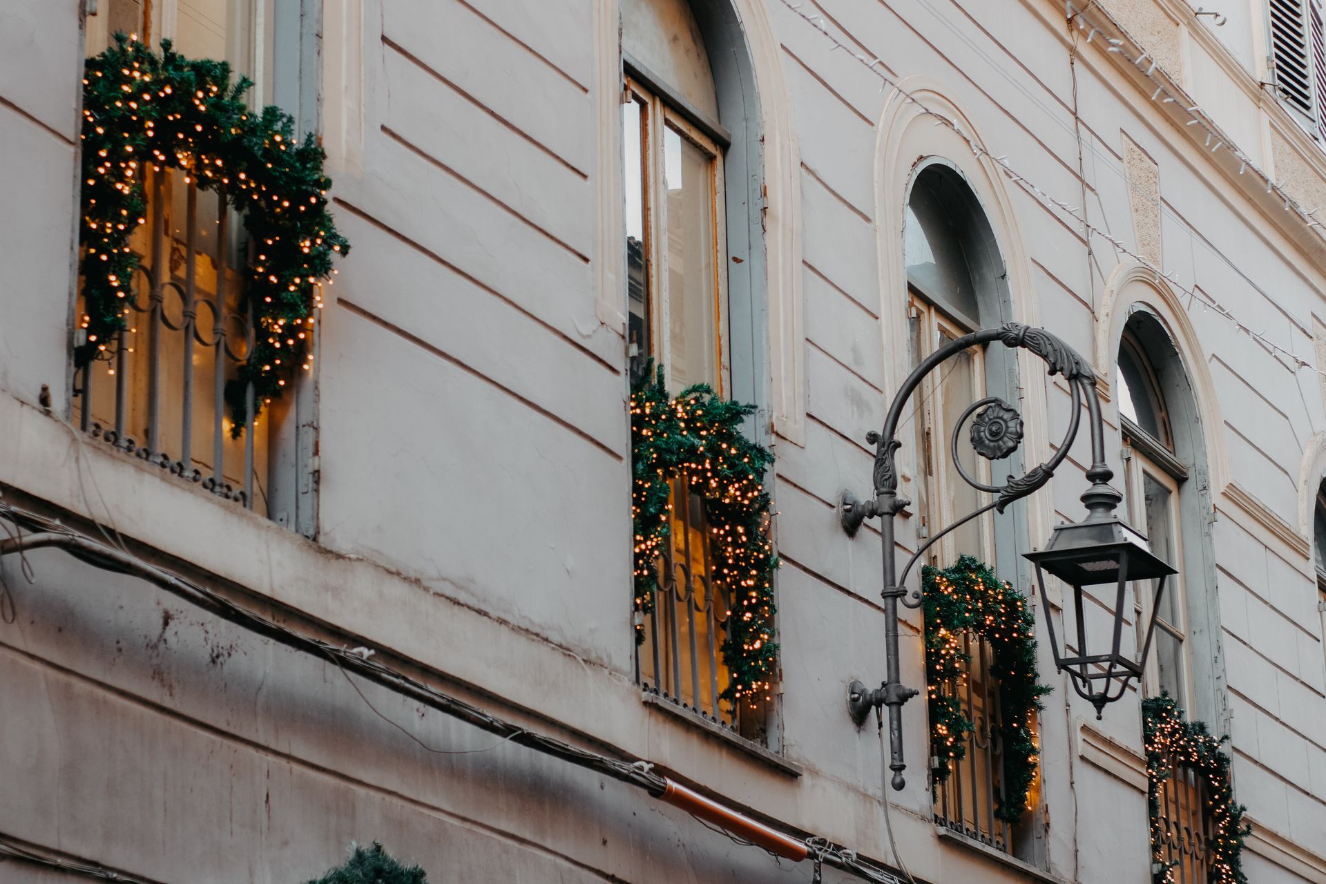 Charming townhouse exterior adorned with Christmas lights and greenery for the holiday season.