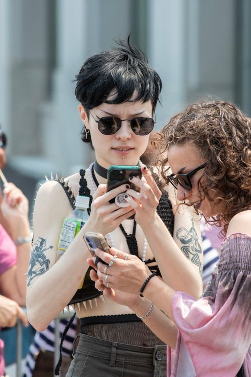 Free Fashionable individuals using smartphones in New York City street showcasing unique style and accessories. Stock Photo