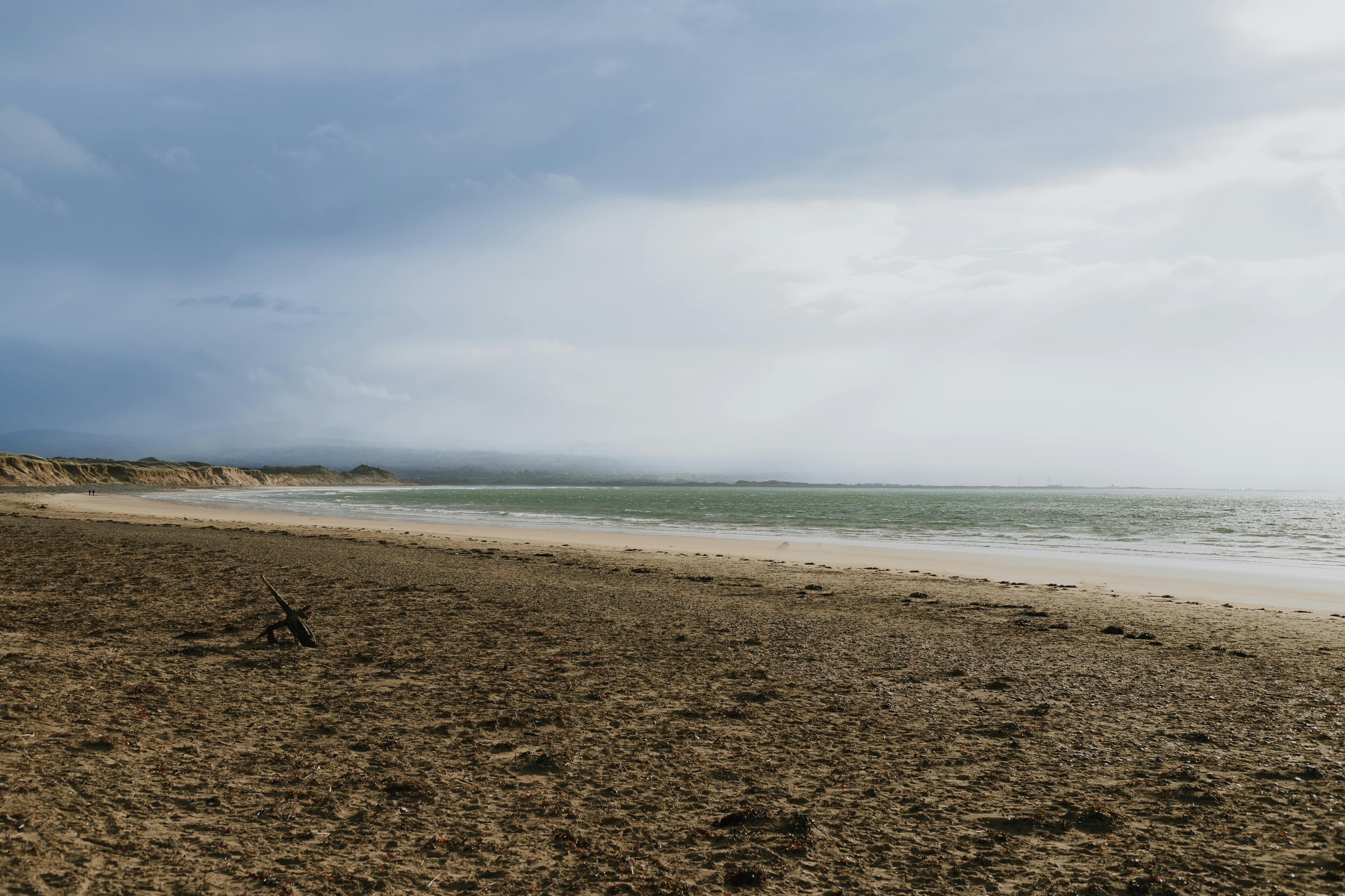 Peaceful overcast day at a quiet beach, featuring smooth sand and gentle waves.
