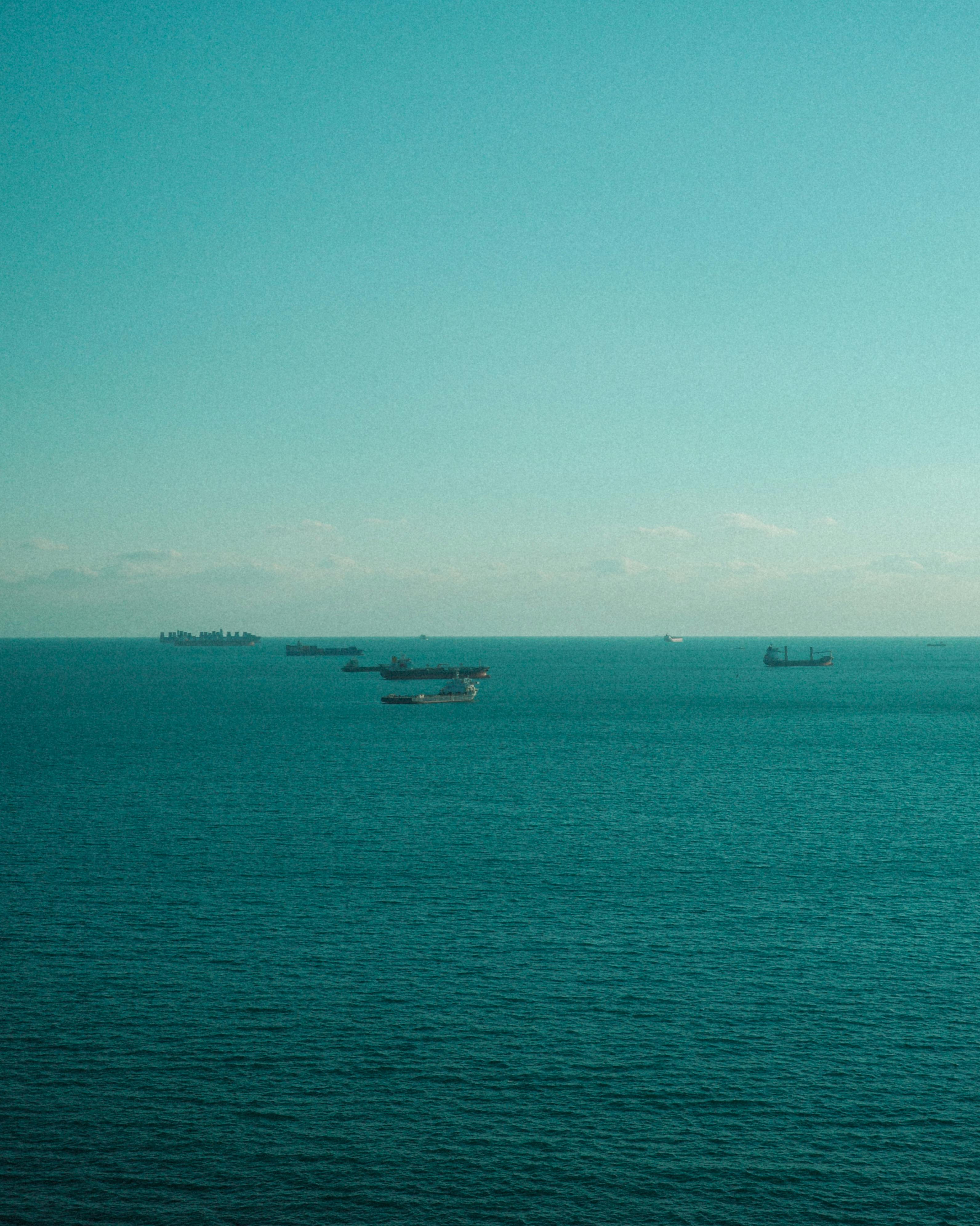 A serene view of cargo ships on the horizon in Busan, South Korea, under a clear sky.