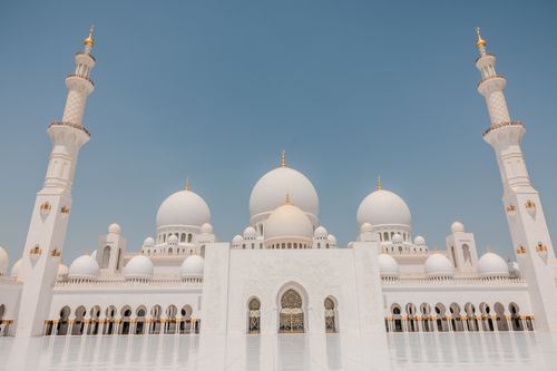 Free White domes and minarets of Sheikh Zayed Grand Mosque framed by a clear blue sky, exemplifying Islamic architecture. Stock Photo