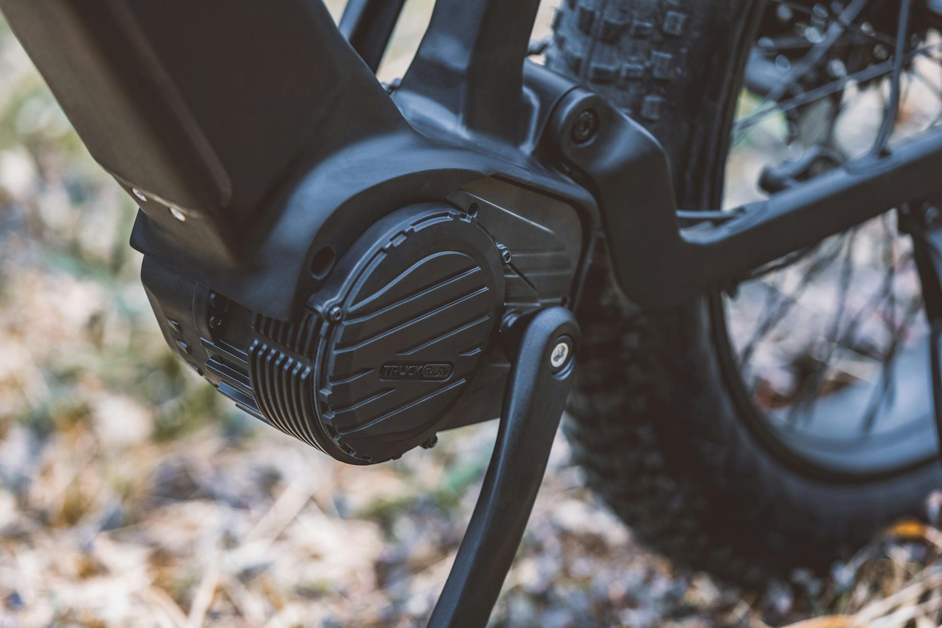 Detail view of an electric bike pedal and motor on a forest trail.