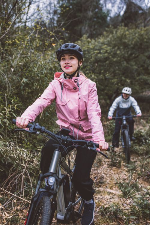 Free Active couple riding mountain bikes through a scenic forest trail, enjoying the autumn outdoors. Stock Photo