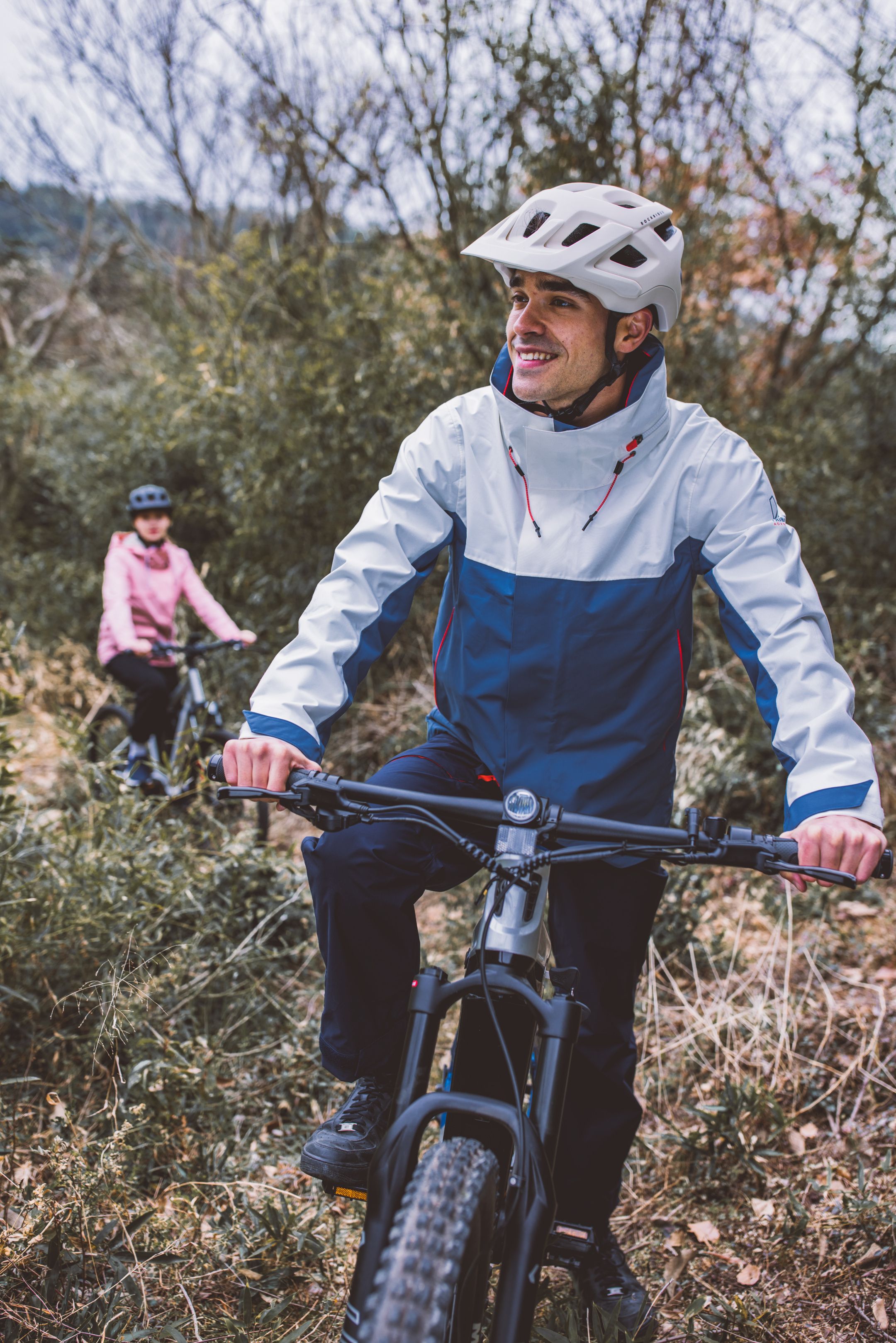 A joyful couple mountain biking through lush trails in autumn, showcasing outdoor adventure and active lifestyle.