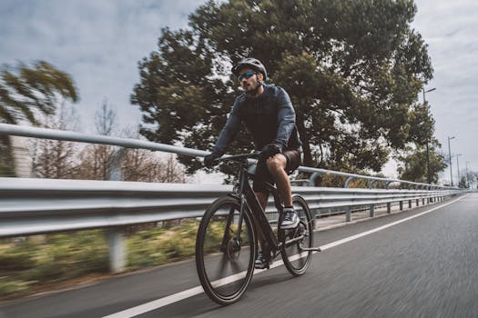 A cyclist rides a bicycle on an asphalt road surrounded by greenery, showcasing an active lifestyle.