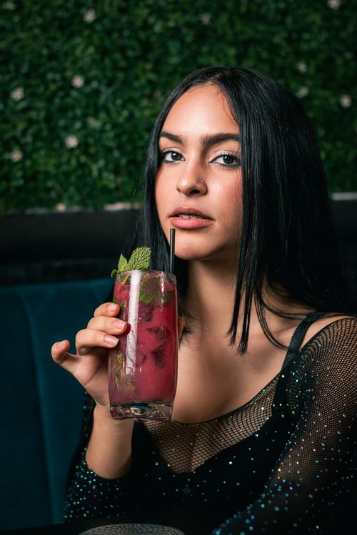 Free A young woman savoring a raspberry cocktail indoors, exuding elegance. Stock Photo