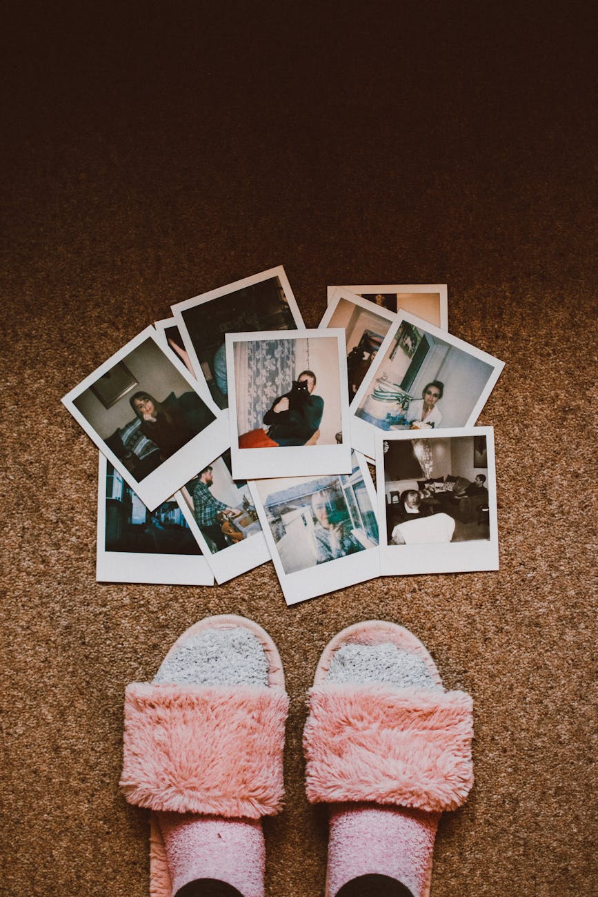 A collection of vintage Polaroids with fuzzy slippers on brown carpet.