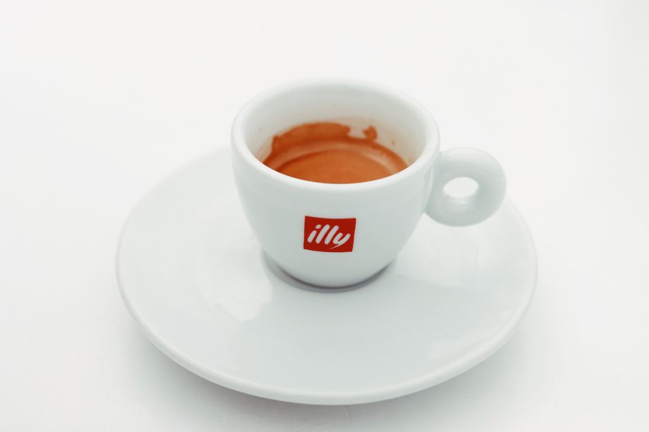 A small white espresso cup with saucer filled with dark espresso coffee