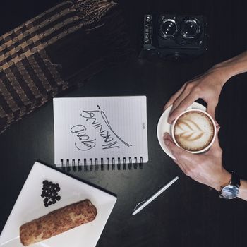 Top view of a cozy coffee setup with a camera and notebook.
