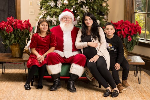 Smiling Pregnant Woman with Children Posing with Santa Claus