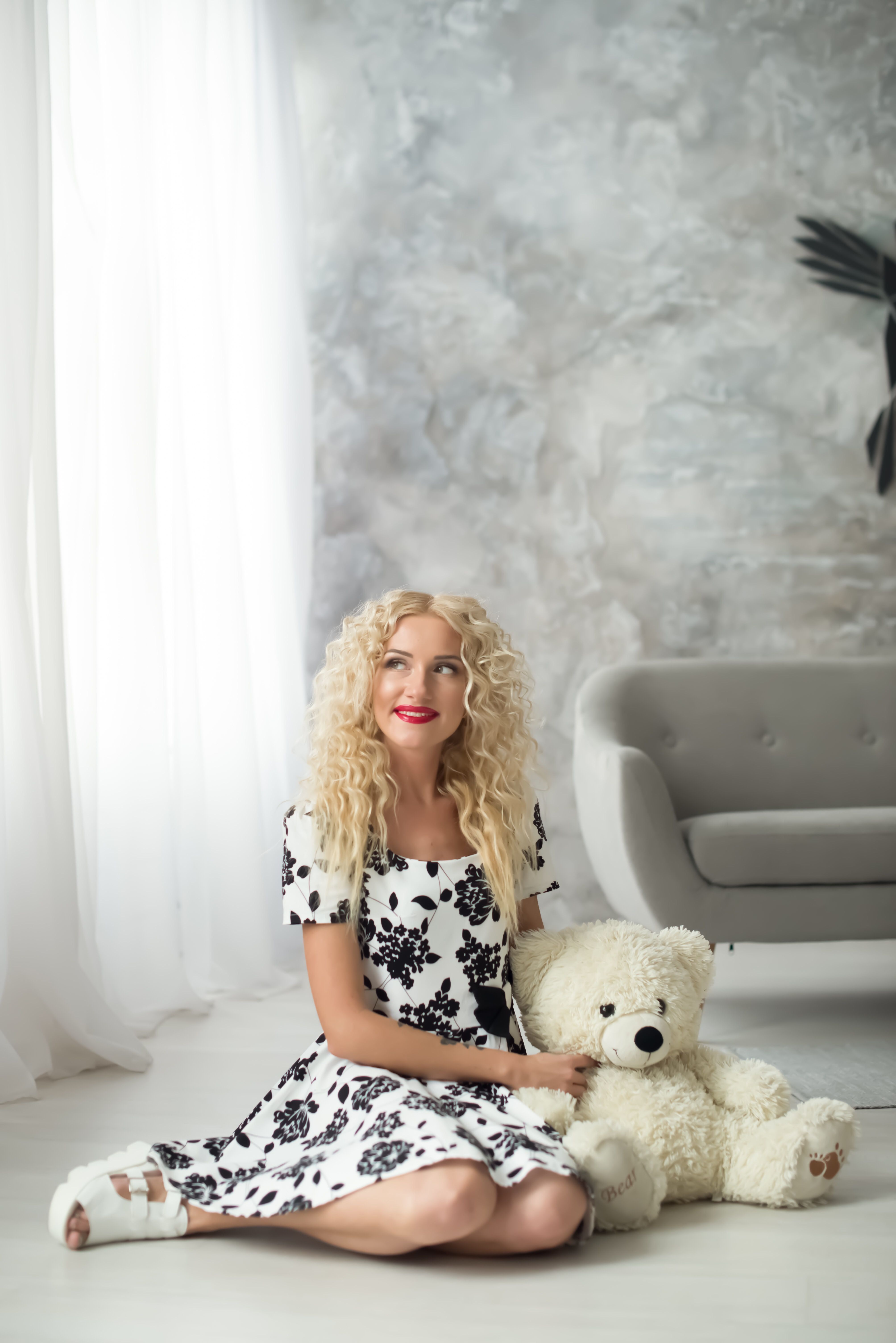 A blonde woman sitting on the floor with a teddy bear · Free Stock Photo