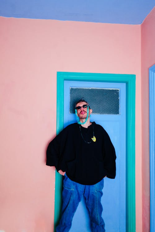 Man Posing by a Door in Sunglasses and a Hoodie