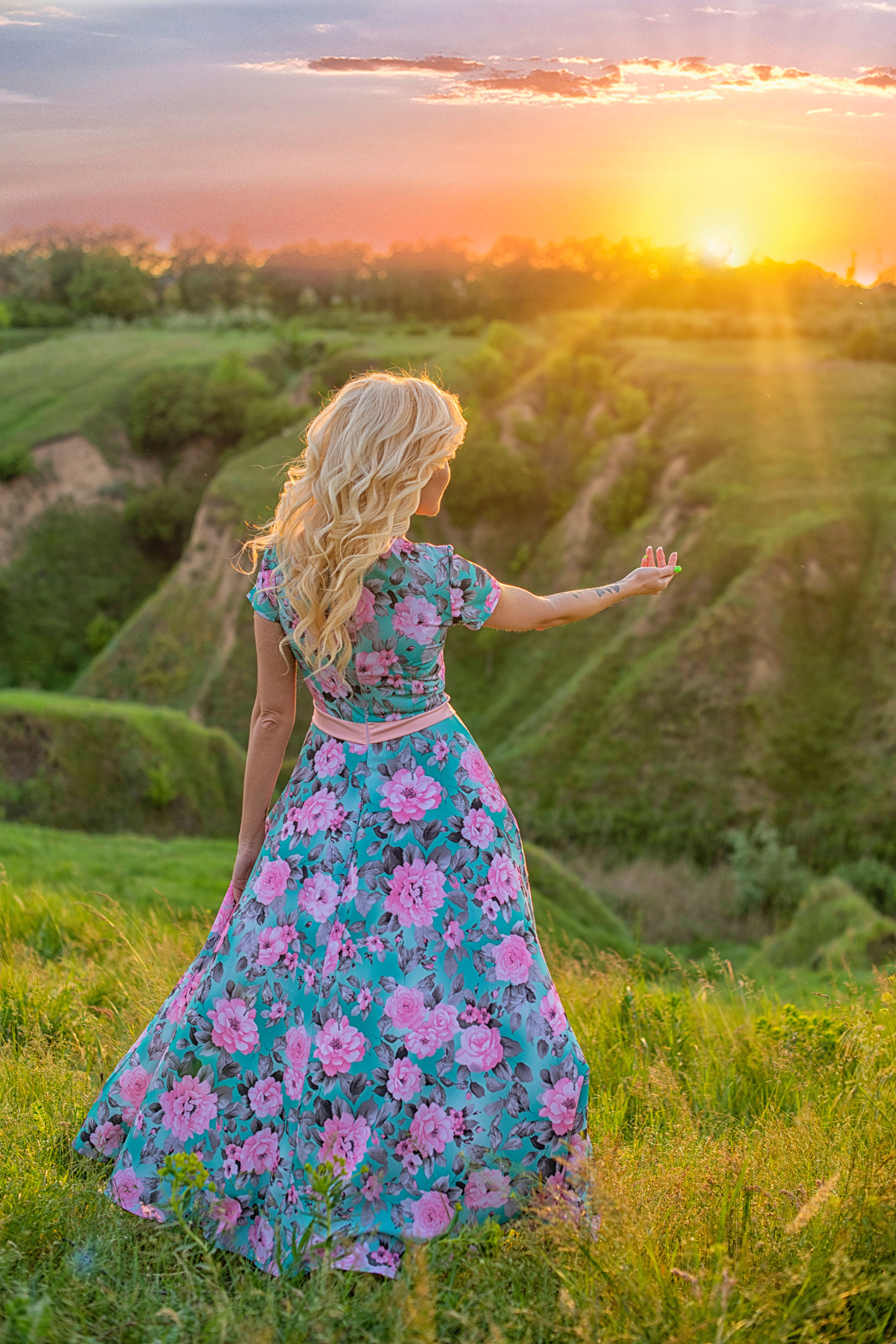A woman in a floral dress is standing in a field at sunset · Free Stock ...