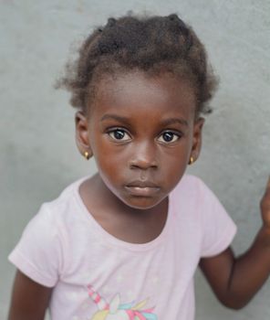 Charming portrait of a young girl wearing a pink t-shirt, showcasing innocence and curiosity.