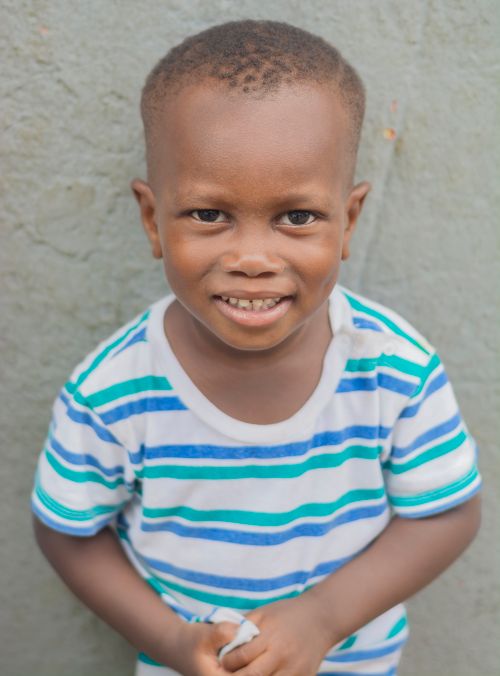 Free Cute child in a striped t-shirt smiling warmly against a neutral background. Stock Photo