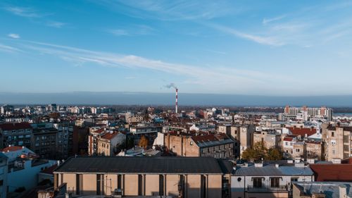 Free Aerial view of Beograd, Serbia, featuring rooftops, buildings, and a smokestack under a clear blue sky. Stock Photo